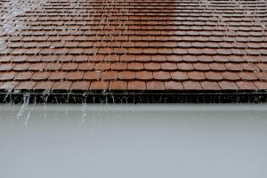 A photo of a roof in the rain, with water falling off.